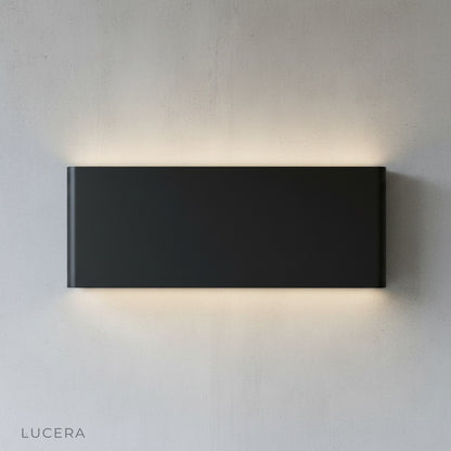 Lucera Cadmium wall lamp in bedroom reading nook casting inviting glow