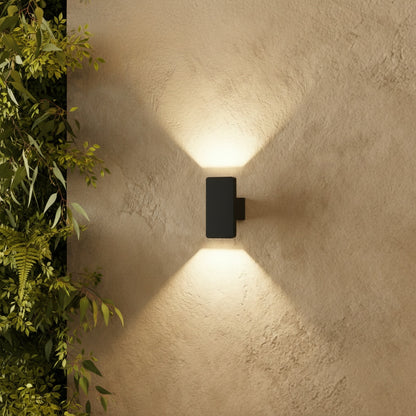 modern black outdoor wall lamp illuminating a cozy patio seating area at dusk