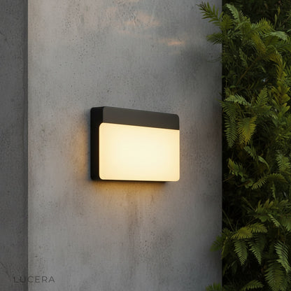 modern black aluminum wall lamp illuminating a contemporary patio at dusk