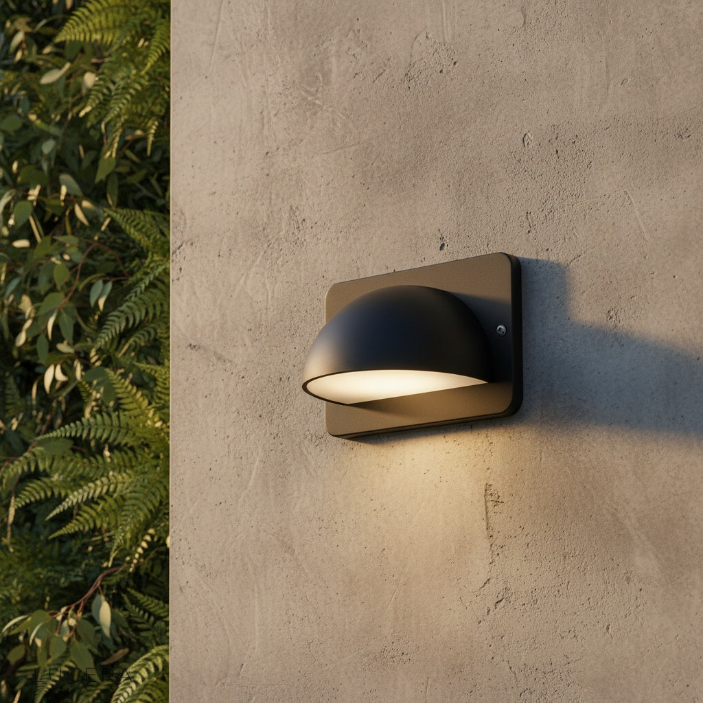 modern black outdoor wall lamp illuminating a brick patio wall at dusk