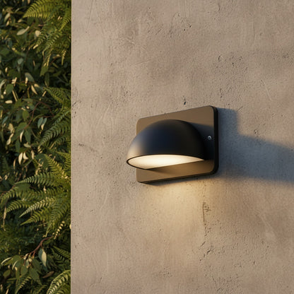 modern black outdoor wall lamp illuminating a brick patio wall at dusk