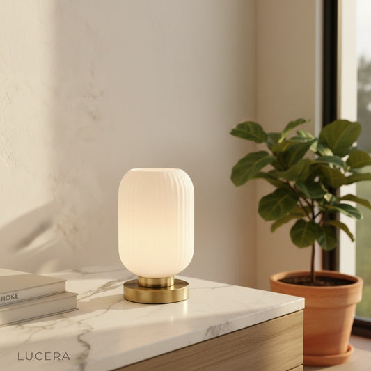 modern ribbed glass table lamp with brass base on wooden console in living room