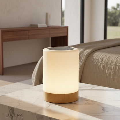 Janus Table Lamp glowing on a modern bedside table in a cozy bedroom at dusk