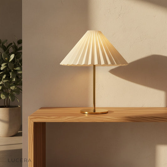 Ysabel Table Lamp with brass finish and pleated fabric shade on a wooden side table in a cozy living room