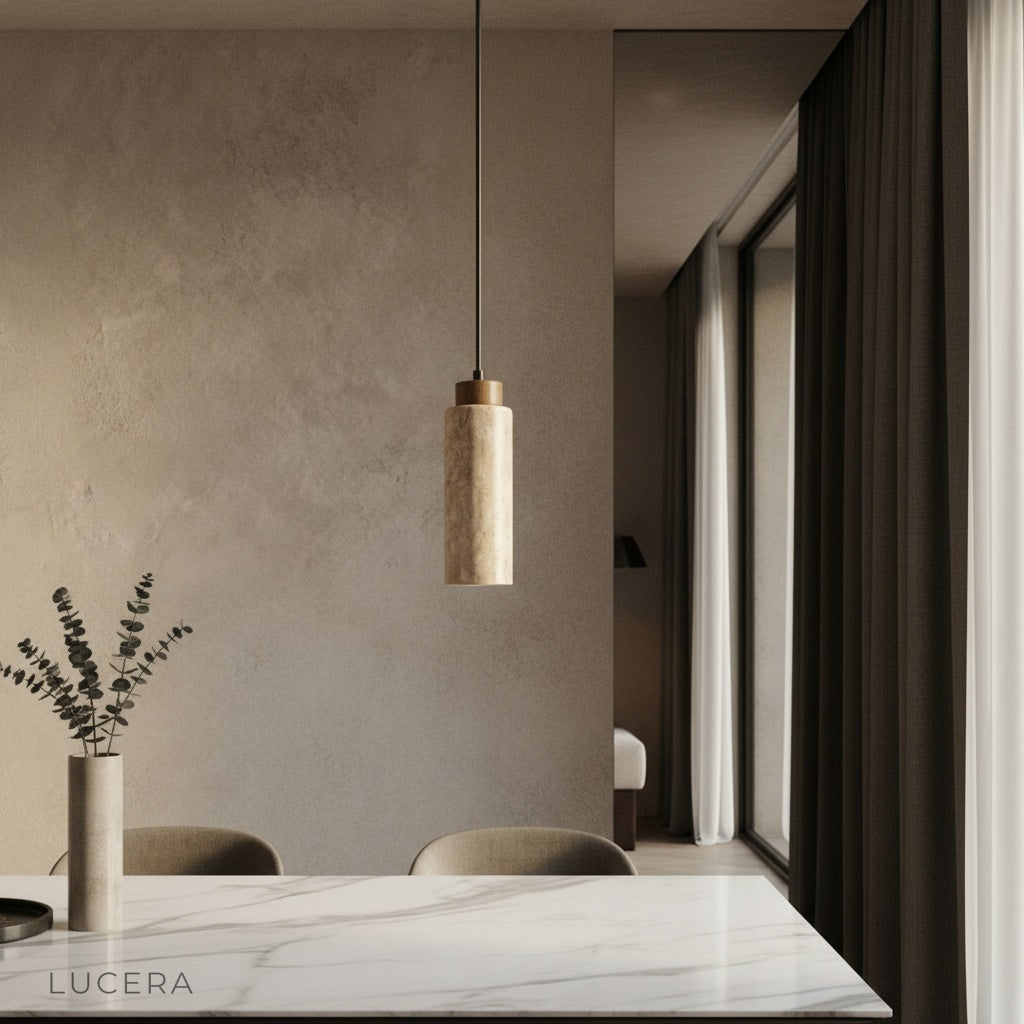 Clandestine travertine pendant light glowing warmly above a neutral wood dining table in a modern living room