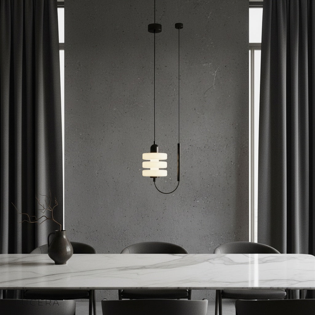 Bastian pendant light with black iron frame and frosted glass glowing warmly in a modern living room