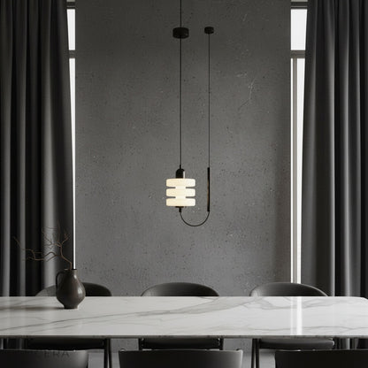 Bastian pendant light with black iron frame and frosted glass glowing warmly in a modern living room
