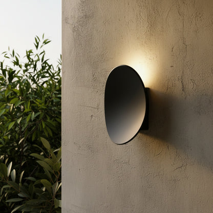 black yard wall lamp glowing on modern patio at dusk