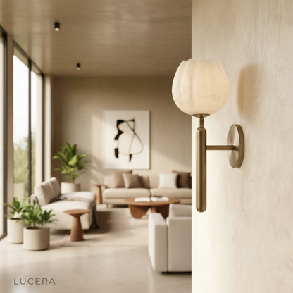 Madeira alabaster wall lamp glowing warmly above a bedside table in a serene bedroom