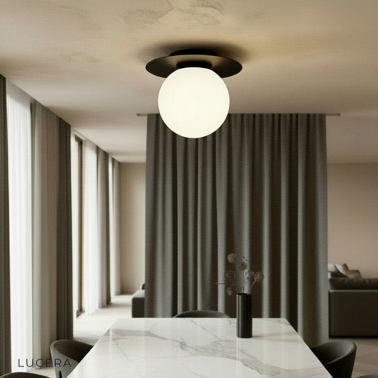 gold Bijou ceiling light glowing in modern living room with glass ball shade
