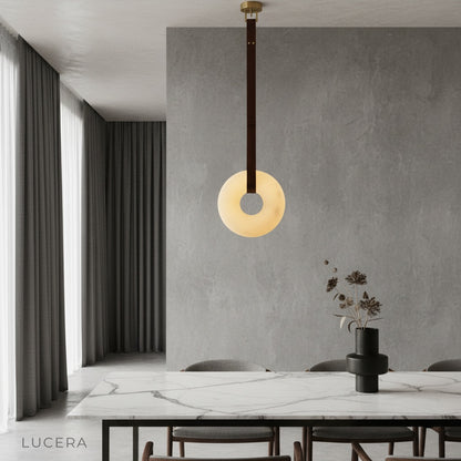 Butte Alabaster pendant light glowing above modern dining table in elegant living room
