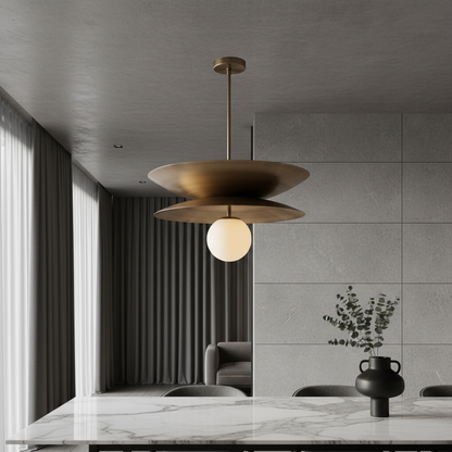 Tremulous pendant light over kitchen island with brass discs and glowing glass globe
