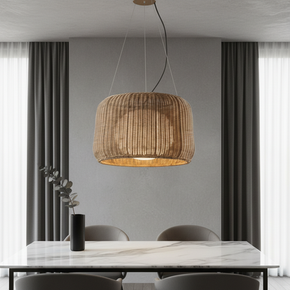 Zealous pendant light hanging over a dining table with woven rattan shade casting warm glow