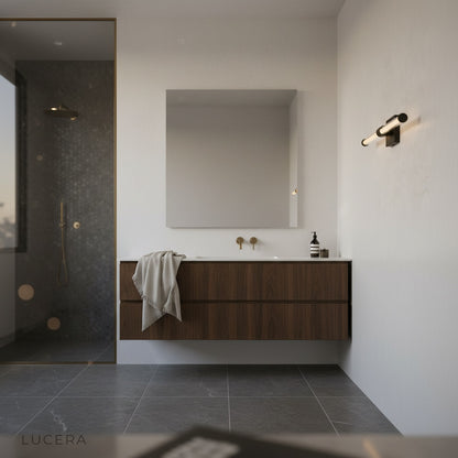 black wall sconce with vertical glass bars casting soft light in spa bathroom
