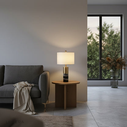 Essere Table Lamp casting soft glow on bedroom nightstand with linen bedding and neutral tones