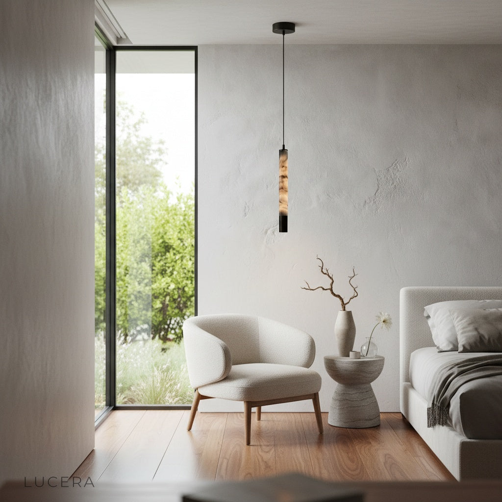 Yseult pendant light glowing warmly in a dark interior with stainless steel details and organic stone form