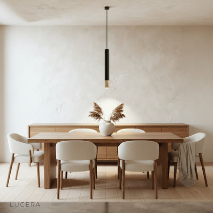 Fascinate pendant light glowing warmly above a wooden dining table in an evening setting