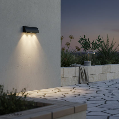 Yarn outdoor wall lamp illuminated at dusk casting warm glow on brick facade