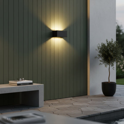 sleek outdoor wall lamp glowing against dark stone facade in nighttime garden setting