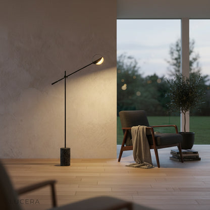 Memento Floor Lamp next to a floor-to-ceiling window with natural daylight and sheer curtains