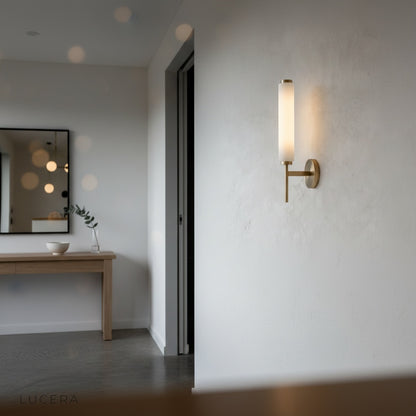 Boreas wall lamp over a console table with dried flowers and mirror in entryway
