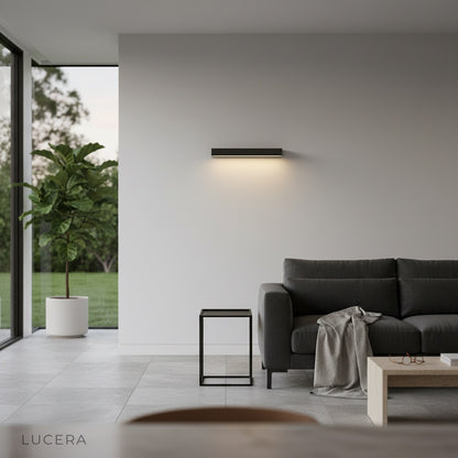 Goccia wall lamp as nightlight on modern stucco wall, moonlit garden background