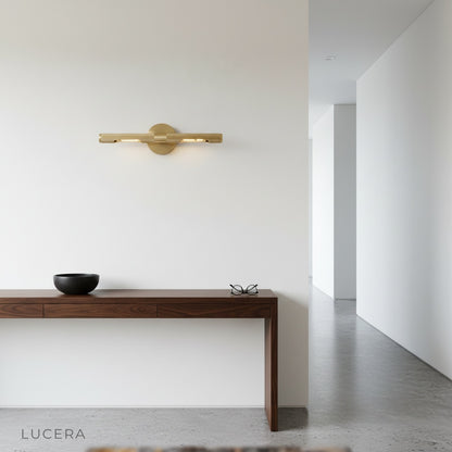 Keziah brass mirror light styled in cozy bedroom corner with warm brass tones